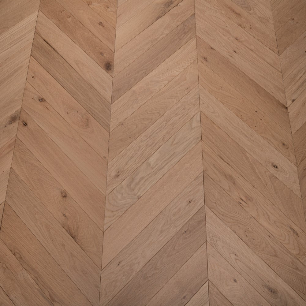 Light natural chevron wood flooring with oiled surface and angled plank pattern.