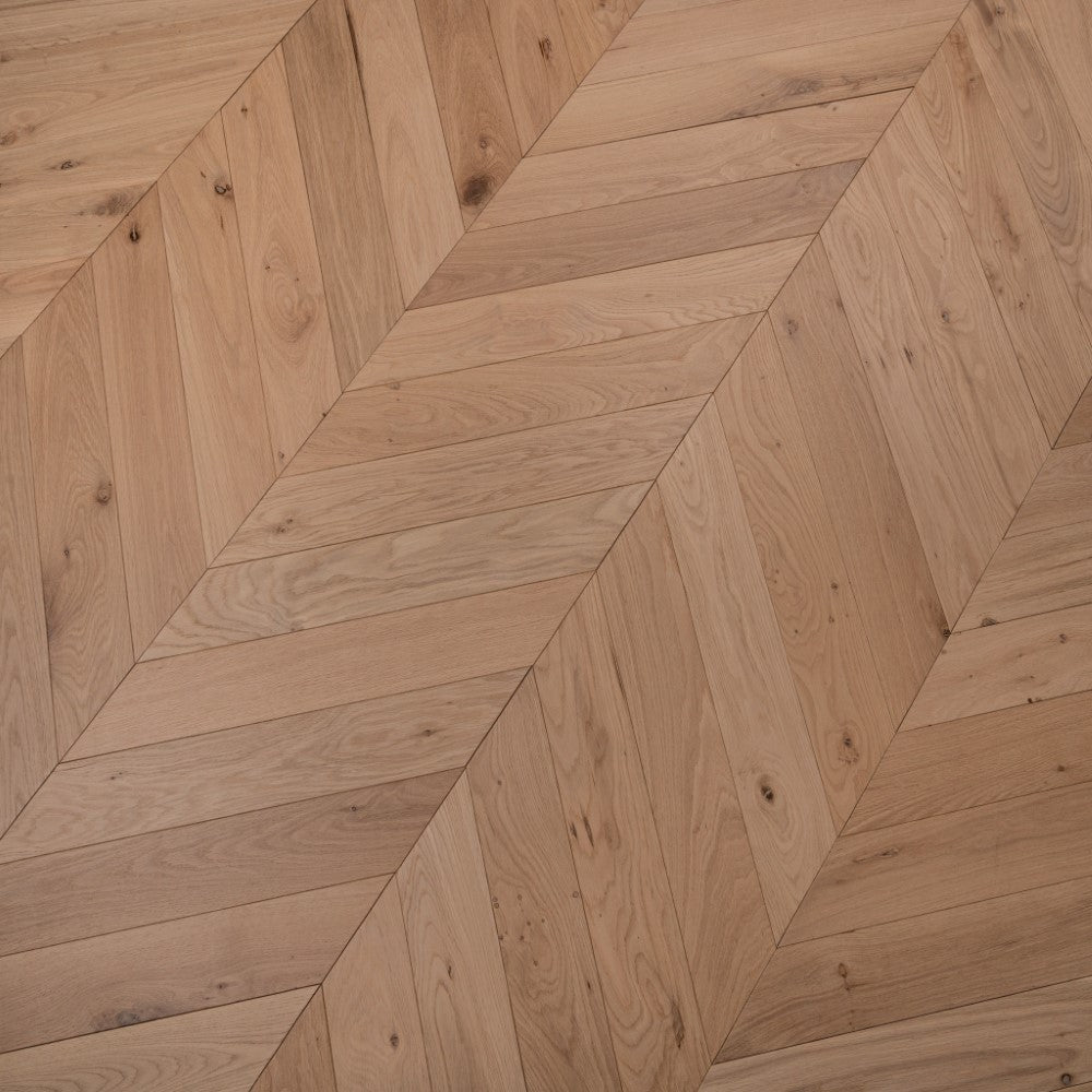 Light natural oiled chevron wood flooring showing overlapping diagonal plank rows.