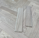 Engineered herringbone oak floor panels laid with light gray-toned wood grain