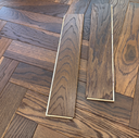 Engineered herringbone wood flooring in gray and brown tones, rectangular planks