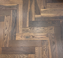 Engineered herringbone wood flooring showing gray and tan plank tones