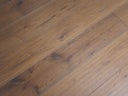 Engineered light brown wood flooring with hand-scraped brushed texture and visible knots