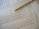 Engineered oiled herringbone wood flooring close-up, light beige planks and joints