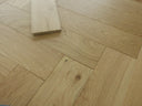 Herringbone wood flooring with light oak tones and visible knots, brushed UV oiled