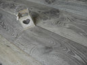 Distressed charcoal grey wood-look hard wax oiled flooring with plank seams and a cutout