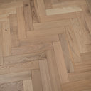 Light wood parquet herringbone flooring with varied plank widths and grain