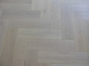 Light white-oiled engineered wood flooring with staggered herringbone planks and seams