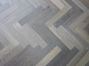 Engineered herringbone wood flooring with light and cool grey plank arrangement