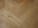 Herringbone wood flooring in light tan, diagonal planks with visible wood knots