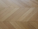 Natural wood chevron flooring with diagonal seams and V-shaped plank joints