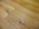 Engineered wood flooring with honey-gold boards, pronounced knots and dark grain flecks