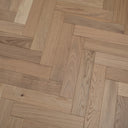 Light wood herringbone parquet flooring showing natural knots and wood grain