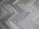 Engineered herringbone wood flooring showing mixed grey plank pattern and grain