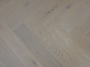 White oiled herringbone wood flooring close-up of light wood grain