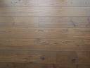 Engineered light brown wood flooring with hand-scraped brushed texture and knots