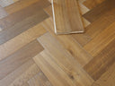 Smoked herringbone engineered wood flooring with a sample board on top