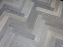 Engineered herringbone wood flooring with alternating light and dark grey tones