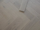 White oiled herringbone wood flooring plank sample piece with cut edge
