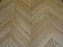 Chevron parquet wood flooring in light natural tones with visible grain lines