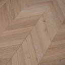 Unfinished light wood chevron flooring boards with visible grain and small knots