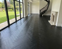 Dark gray engineered herringbone wood flooring across open room floor