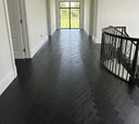 Dark gray herringbone engineered wood flooring, hallway view with railing