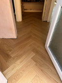 Light wood-look herringbone flooring with brushed matt finish, hallway angle view