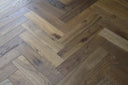 Smoked engineered wood flooring with brushed herringbone pattern, cool gray and brown tones