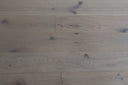 Light wood-look flooring showing straight plank layout and swirling grain, matte finish