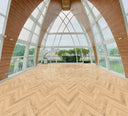 Laminate herringbone flooring in light oak, wide view of diagonal chevron pattern