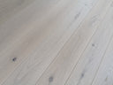 Whitewashed wood flooring planks with gray grain and scattered knots