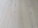 Light white wood flooring planks with visible seams and natural knots