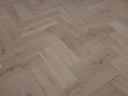 Herringbone wood flooring showing light planks, wood grain knots, and tight pattern lines