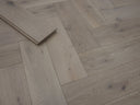 Herringbone wood flooring in light neutral tone with narrow plank spacing and joints