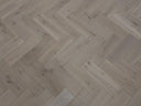 Herringbone wood flooring with light gray-beige planks and visible herringbone pattern