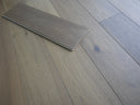 Engineered wood flooring planks laid flat, with one loose board overlapping on the floor