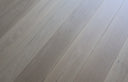 Light gray engineered wood flooring planks with subtle knots and wood grain, visible seams