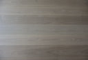 Light gray engineered wood flooring with long plank boards and flowing wood grain lines