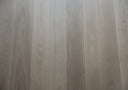 Light gray engineered wood flooring planks with pale tones, knots, and natural grain