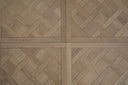 Light oak parquet wood panel with interlocking herringbone tiles and matt finish