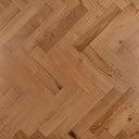 Engineered herringbone wood floor close-up with warm light oak grain and seams