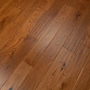 Golden hand-scraped engineered wood flooring with varied grain on long planks.
