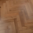 Engineered herringbone wood floor close-up with light oak tones and plank pattern