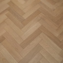 Light wood herringbone parquet flooring with narrow boards and tight alternating chevron lines.