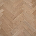 Light tan herringbone parquet wood flooring with natural knots and smooth plank seams