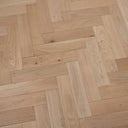 Light tan herringbone wood flooring with varied plank widths and pronounced wood grain