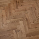 Engineered wood herringbone floor in honey light brown with brushed texture and knots