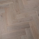 Engineered herringbone wood flooring close view, brushed white planks with wood grain texture