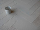 White brushed matte engineered wood herringbone flooring with staggered plank pattern