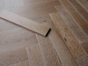 Smoked white engineered herringbone wood flooring with light gray plank texture
